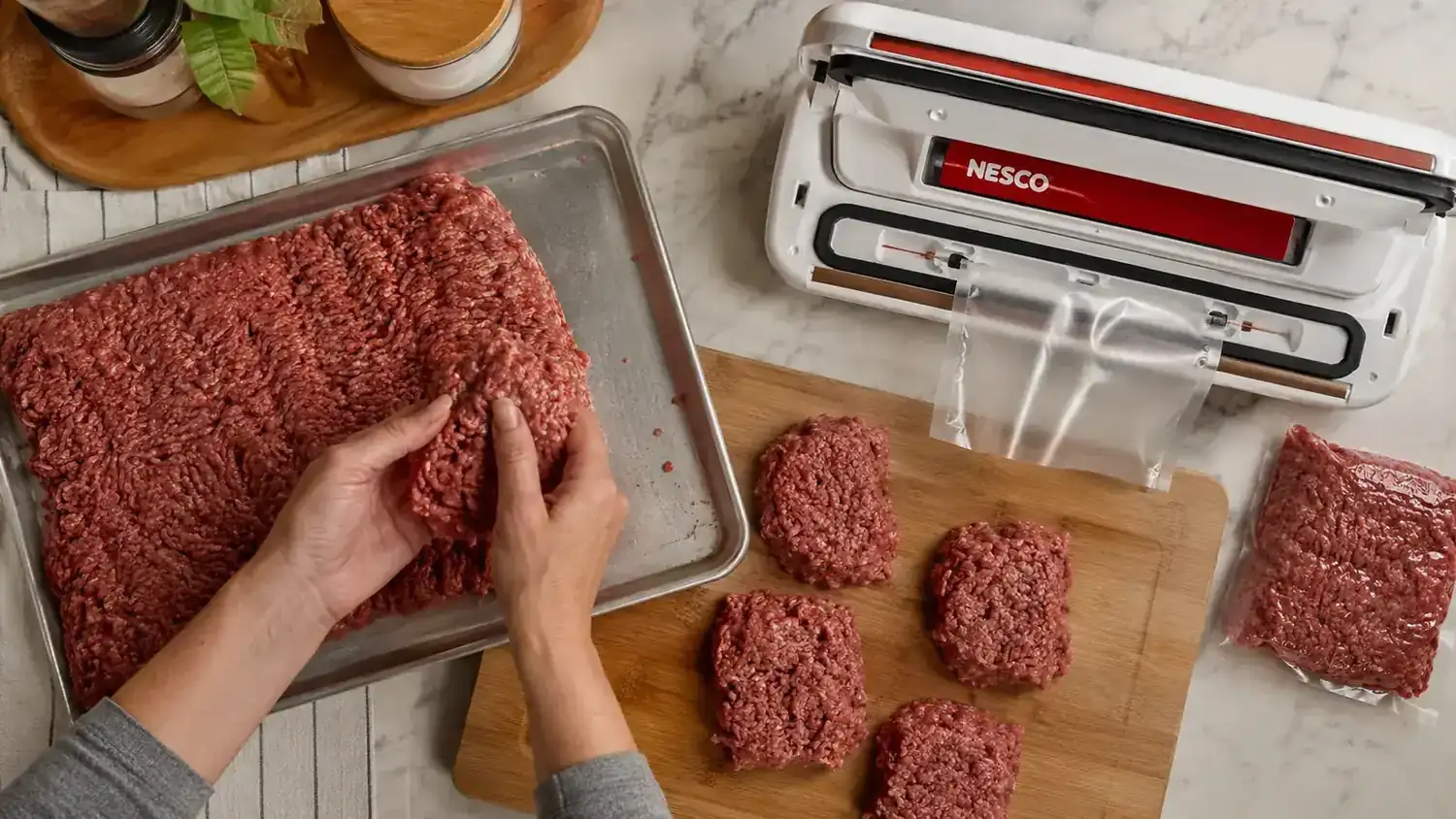 Home cook portioning bulk ground beef into individual vacuum sealed bags on a cutting board