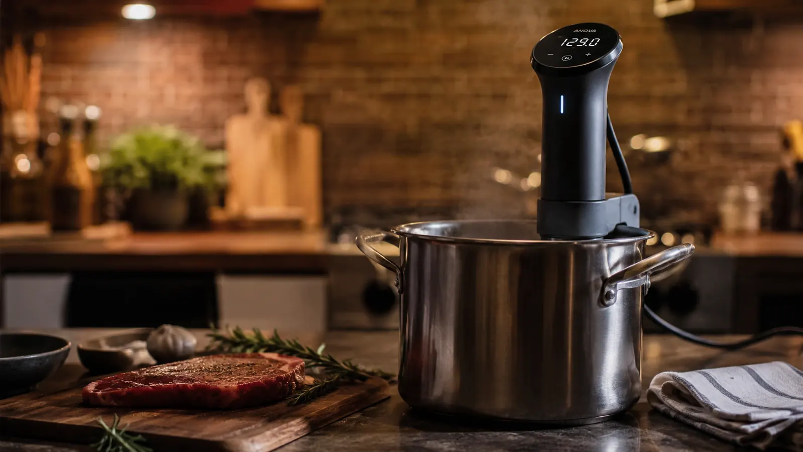 Anova Precision Cooker 2.0 clamped to the side of a stockpot on a kitchen counter with steam gently rising