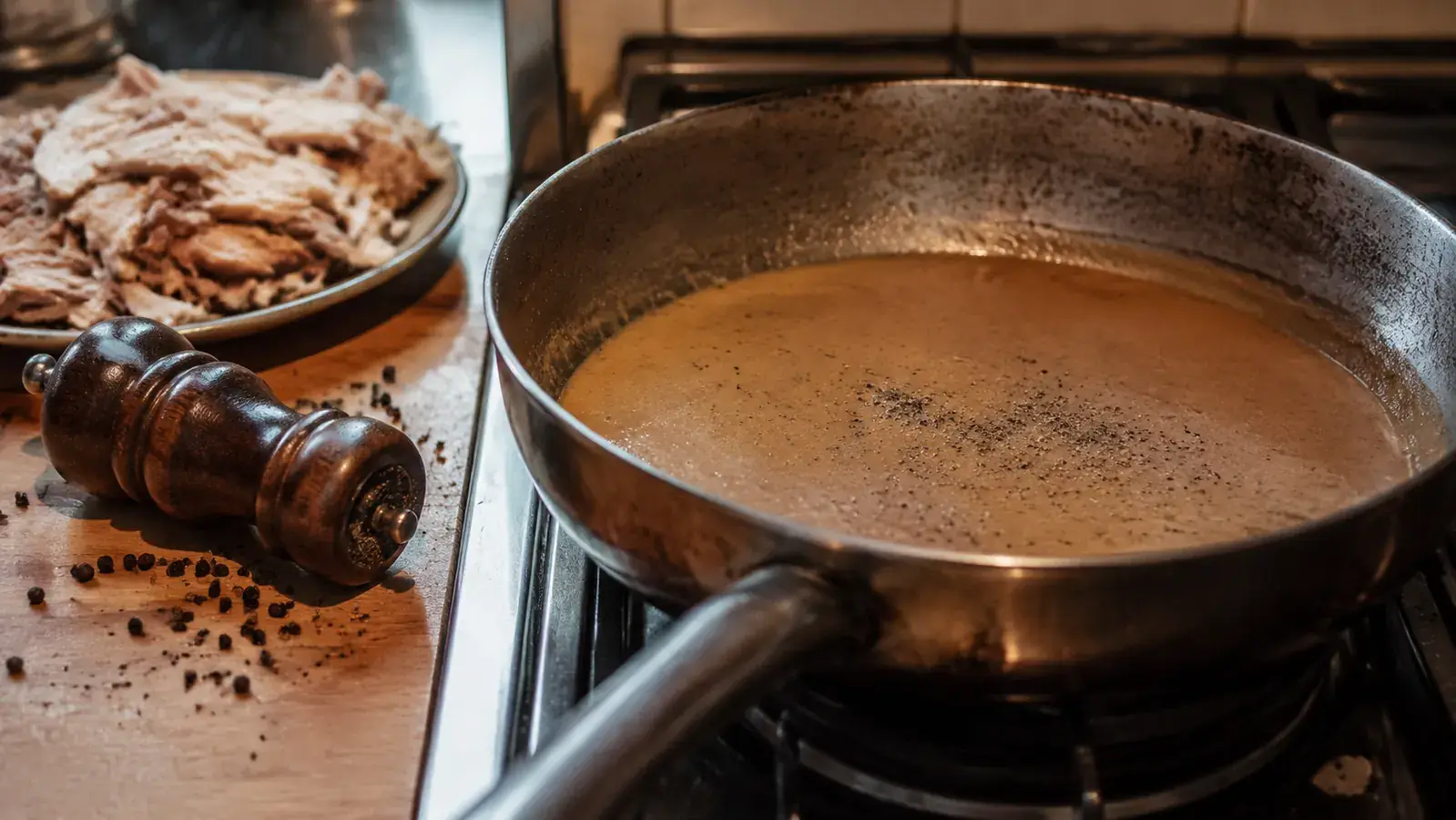 A gluey, over-reduced pan of gravy on the stove next to a stuck wooden pepper mill lying on its side
