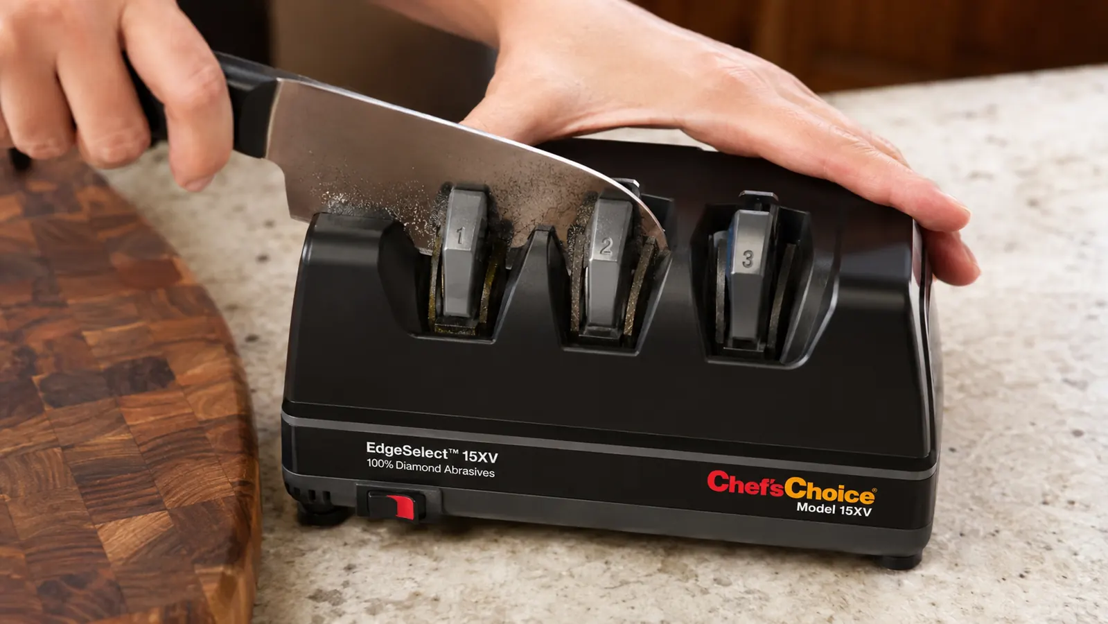 Close-up of a knife blade being drawn through Stage 1 of the Chef'sChoice electric sharpener with sparks of metal dust visible