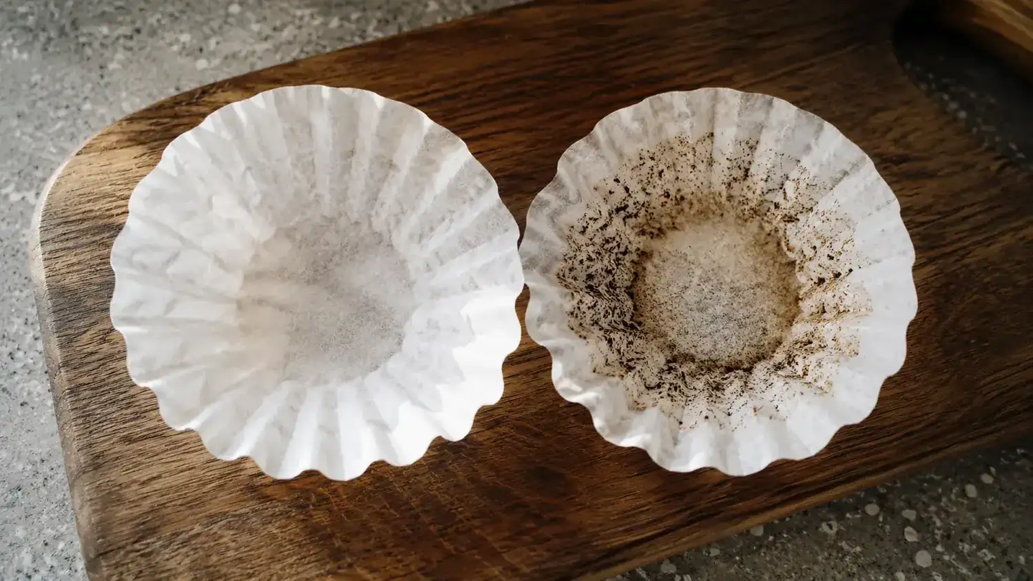 Two coffee filter papers side by side showing the difference in coffee grounds caught after straining each carafe